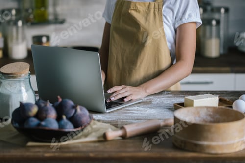 Preview: cropped shot of woman using laptop during pie preparation