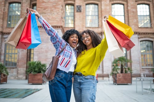 Preview: Happy women friends enjoying shopping holding bags outdoors