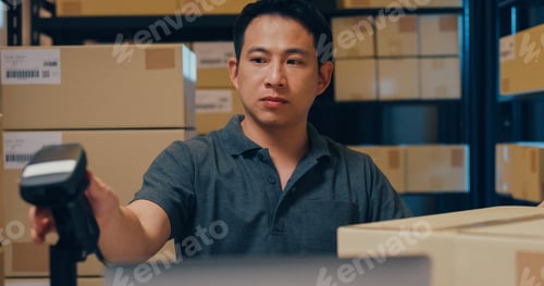 Preview: Close-up Asian man use barcode machine scan data in box and register online order detail in laptop.