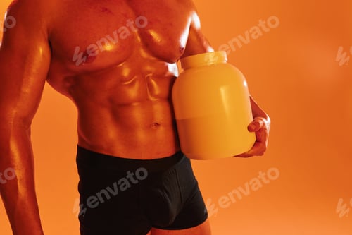 Preview: Man bodybuilder boxer with naked torso with abs holding can muscle growth pills, steroids, doping