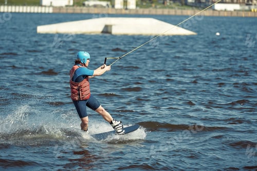Preview: Young man riding wakeboard on a summer lake