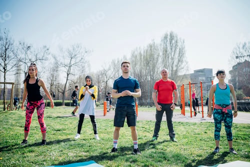 Preview: Calisthenics class at outdoor gym, women and men practicing yoga