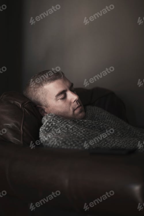 Preview: Mature man wrapped in blanket asleep on armchair