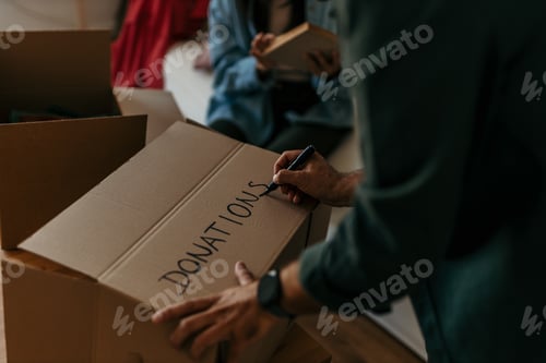 Preview: Person writing donations on a cardboard box