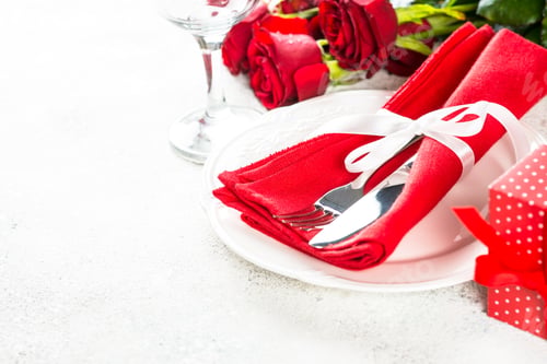 Preview: Romantic holiday table setting with plate, roses and present.