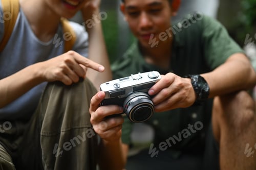 Preview: Couple of hikers with backpacks resting and checking photos on camera in forest
