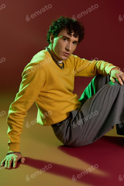 Preview: Handsome man showcases stylish fashion in a vibrant artistic setting with bold colors