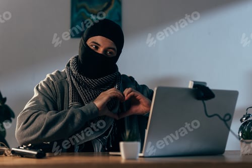 Preview: Criminal in black mask showing heart sign at webcam