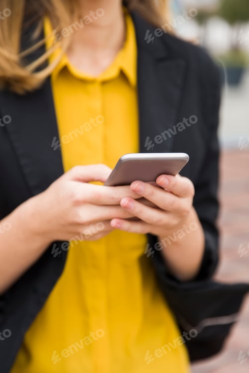 Preview: Executive working with a mobile phone in the street with office buildings in the background