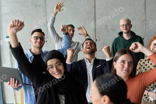 Preview: A diverse team of business professionals ecstatically celebrating their success in a modern office