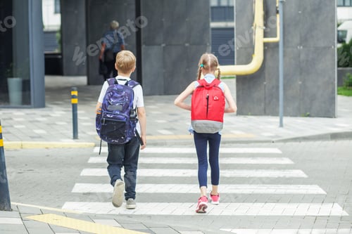 Preview: Back to school. Little pedestrians with backpacks walk to school and cross road at crosswalk