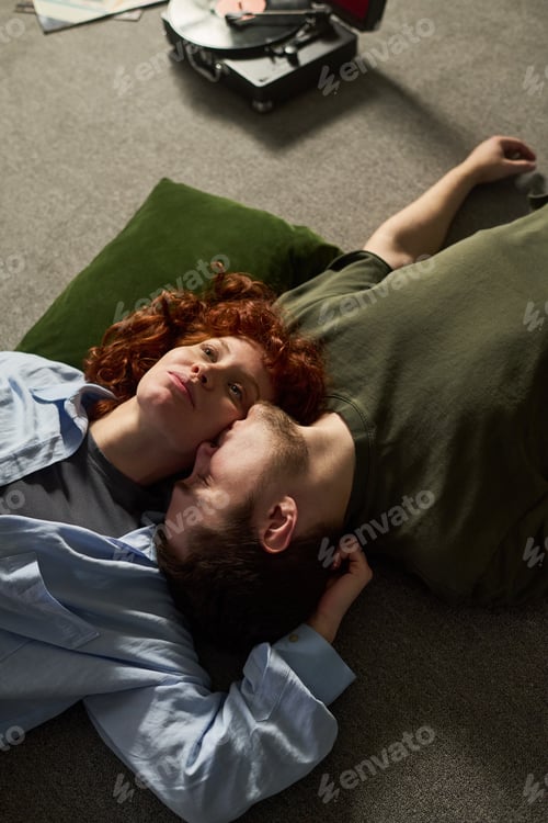 Preview: Young Couple Relaxing Together on Floor Listening to Vinyl Record