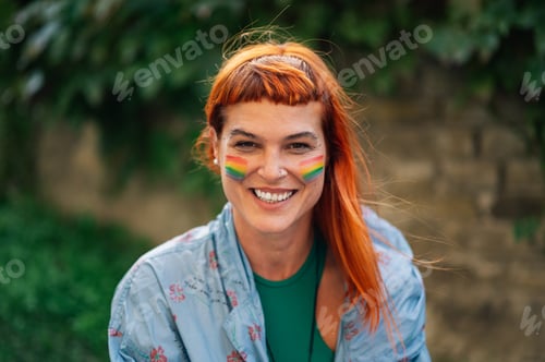 Preview: Portrait of smiling woman with rainbow flag painted on face