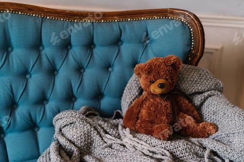 Preview: Brown teddy bear on luxury sofa. Coziness and domestic atmosphere.