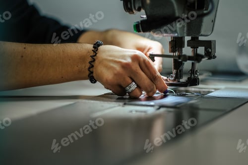 Preview: Closeup shot of female hands operating an industrial sewing machine