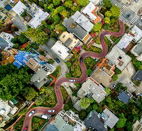 Preview: Aerial view of a residential city area, with road descending a hillside with eight hairpin turns.