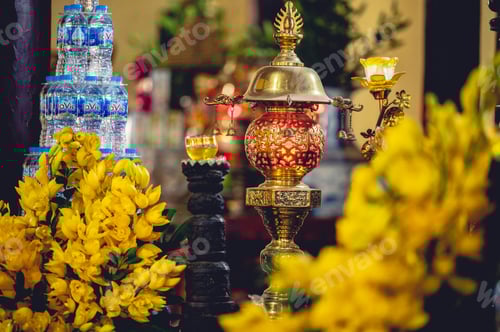 Preview: Closeup shot of Buddhist ornaments,water bottles and yellow flowers inside a temple in Vietnam