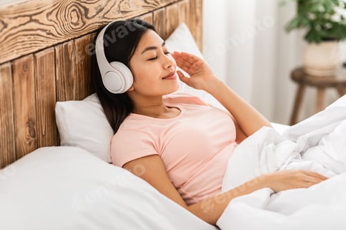 Preview: Chinese Girl In Earphones Listening To Podcast Lying In Bed