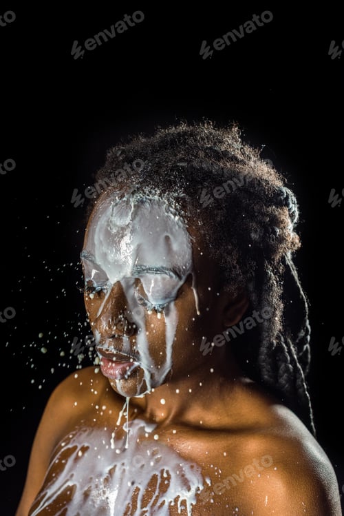 Preview: milk spilled on face and naked body of beautiful young african american woman isolated on black