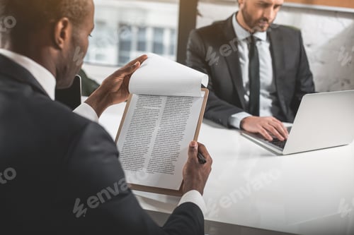 Preview: Important Agreement. Back View Of Young Professional African Man Is Reading Document. He Is Sitting