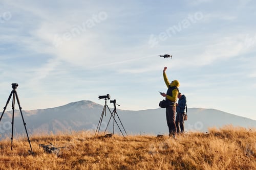 Preview: Male photographers standing and working at majestic landscape of autumn trees and mountains