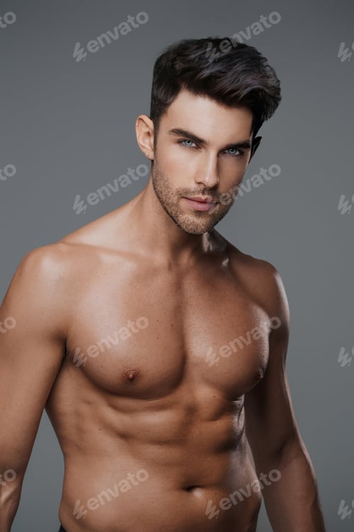Preview: Close-up portrait of a sexy brunette male model with a bare torso against a gray background