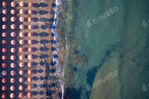 Preview: Aerial shot of colorful beach umbrellas lined up along the shoreline.