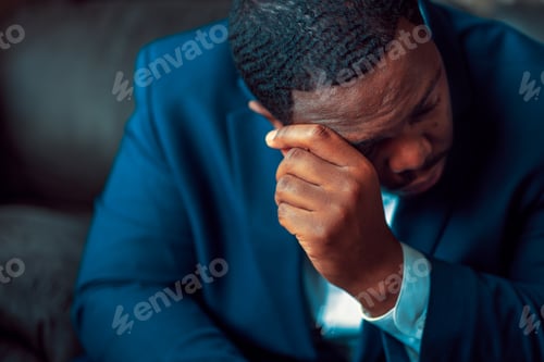 Preview: Black or African American business man sitting down looking anxious and depressed