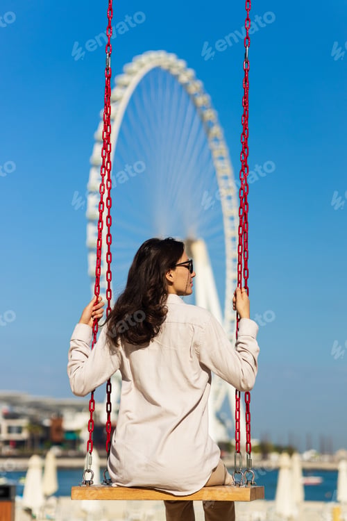 Preview: Happy woman tourist look at one of the largest Ferris Wheels in the World