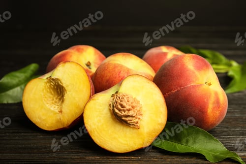 Preview: Fresh juicy peaches and leaves on black wooden table