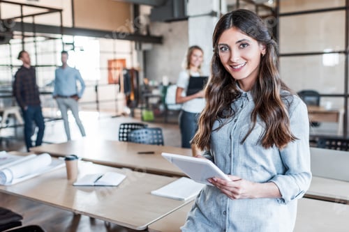 Preview: beautiful young businesswoman using digital tablet and smiling at camera in office