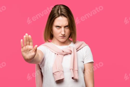 Preview: aggressive young woman showing stop gesture isolated on pink