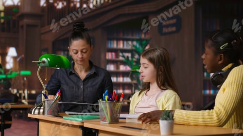 Preview: Caucasian tutor guiding elementary school girls at a library desk