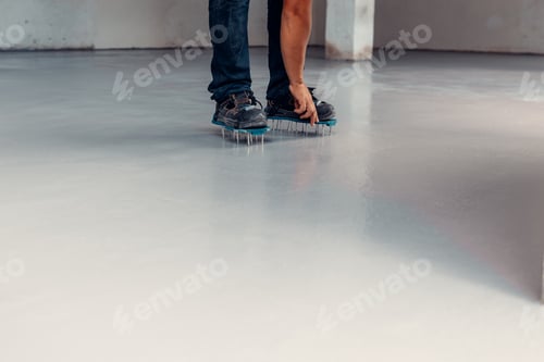 Preview: A construction worker apply grey epoxy resin in an industrial hall