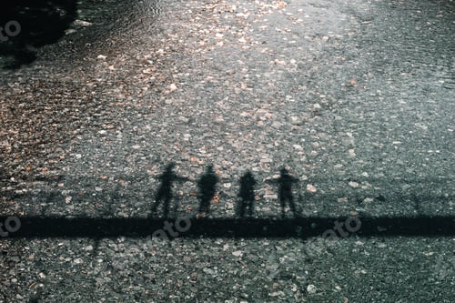Preview: black shadows of four people standing side by side leaning over the railing of a suspension bridge