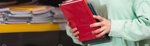 Preview: cropped view of child holding colorful copybooks in stationery store, banner