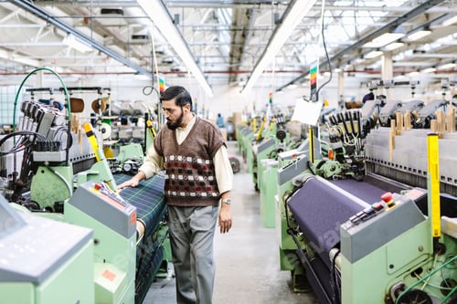 Preview: Male factory worker monitoring weaving machine quality in woollen mill