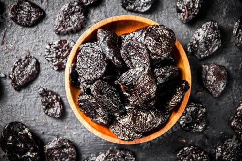 Preview: Prunes in a wooden plate on the table.