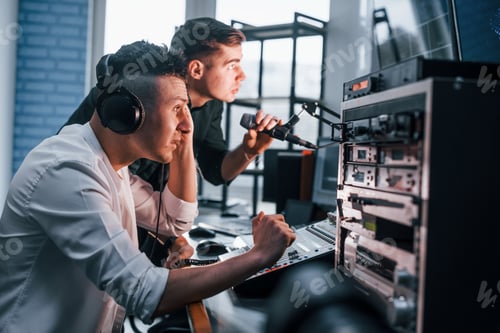 Preview: Conception of teamwork. Two guys is indoors in the radio studio is busy by broadcast
