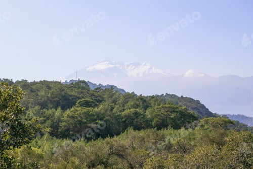 Preview: A beautiful landscape with majestic mountains covered in lush greenery under a clear blue sky.