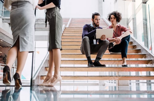 Preview: Group of young businesspeople stitting on a staircase, talking.