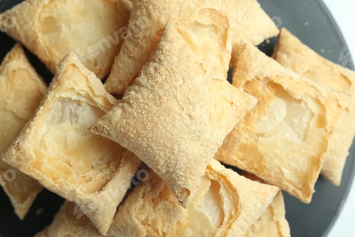 Preview: Top view closeup shot of a pile of square puff biscuits on a black pastry stand