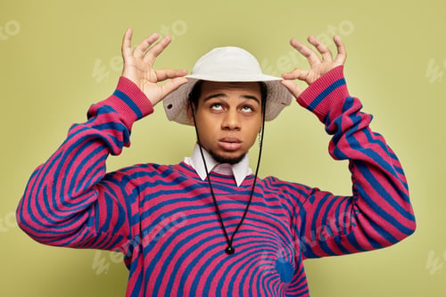 Preview: Stylish young african american man poses playfully against vibrant green backdrop