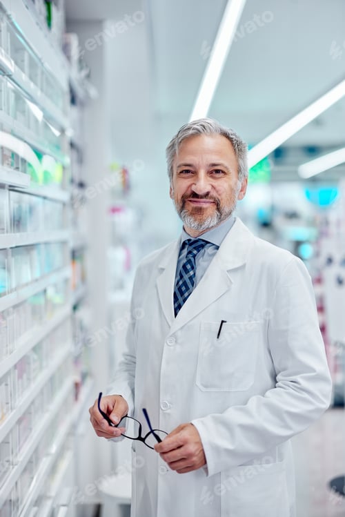 Preview: Portrait of a smiling male pharmacist, dressed in a uniform, holding his glasses.