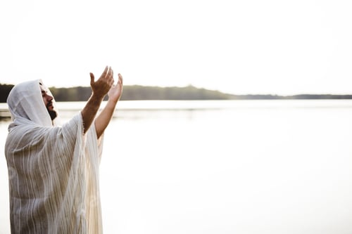 Preview: Jesus Christ with his hands up towards the sky while his eyes are closed and praying