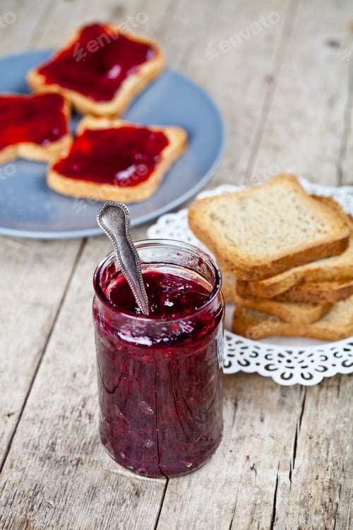 Preview: Homemade cherry jam and fresh toasted cereal bread slices plates closeup on rustic.