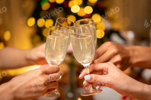 Visualização: Mãos de jovens tilintando com uma taça de champanhe para comemorar e brindando de felicidade