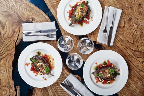 Preview: Half baked eggplants with meat, cheese and tomatoes on white background. Banquet festive dishes