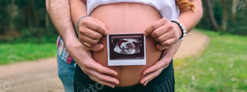 Preview: Female pregnant showing ultrasound scan of baby while her partner holding her belly