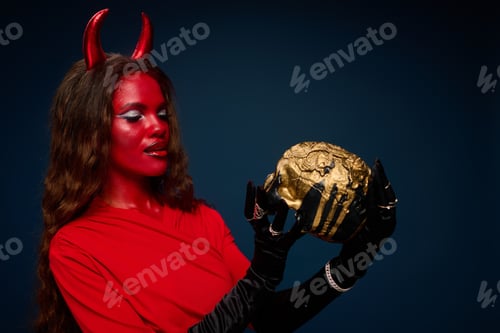 Preview: A captivating woman dressed in a stunning Halloween costume holding a golden skull